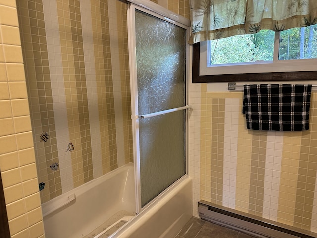 bathroom featuring tile patterned flooring, enclosed tub / shower combo, and baseboard heating