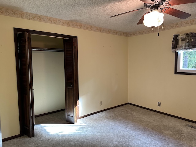 unfurnished bedroom featuring a textured ceiling, a closet, ceiling fan, and carpet