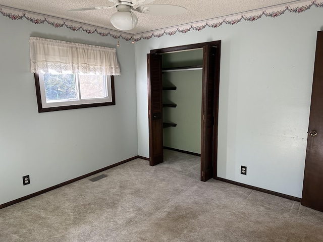 unfurnished bedroom with light colored carpet, a textured ceiling, ceiling fan, and a closet