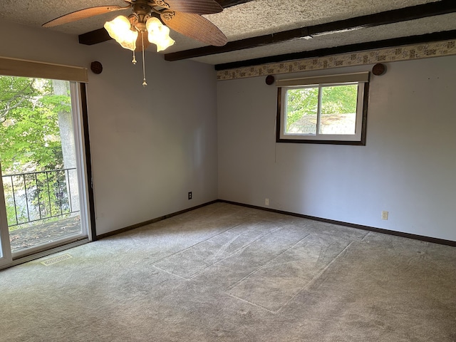 carpeted empty room featuring beamed ceiling and plenty of natural light