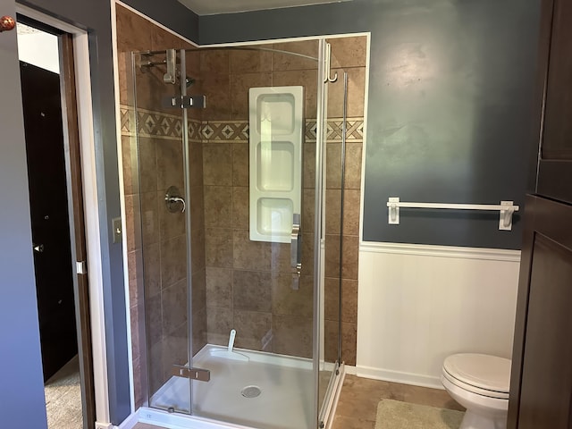 bathroom featuring toilet, an enclosed shower, and tile patterned flooring