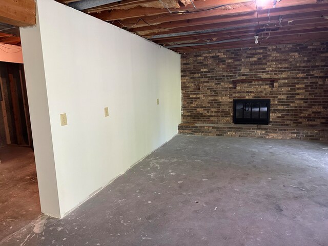 basement with brick wall and a brick fireplace