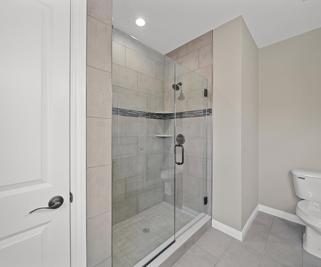 bathroom with baseboards, tile patterned flooring, toilet, and a shower stall