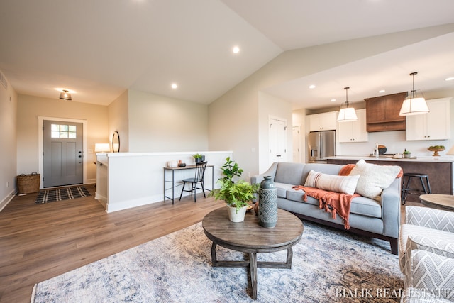 living room featuring light wood-type flooring, sink, and lofted ceiling