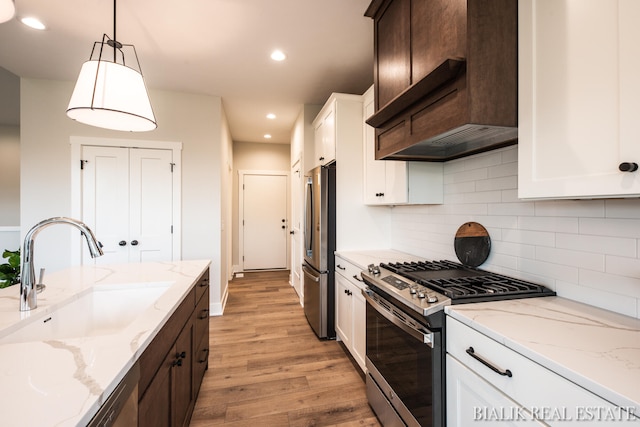 kitchen with stainless steel appliances, light hardwood / wood-style flooring, tasteful backsplash, sink, and white cabinets