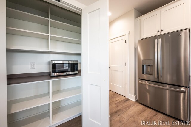 kitchen featuring stainless steel appliances, hardwood / wood-style floors, and white cabinetry