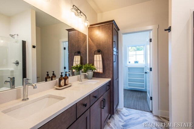 bathroom featuring dual vanity and a shower