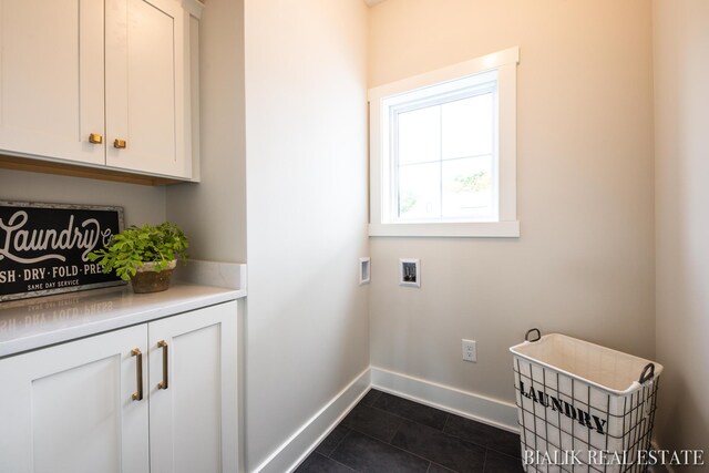 washroom featuring dark tile patterned flooring, cabinets, and washer hookup