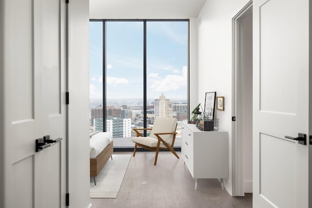 sitting room with floor to ceiling windows and light hardwood / wood-style floors