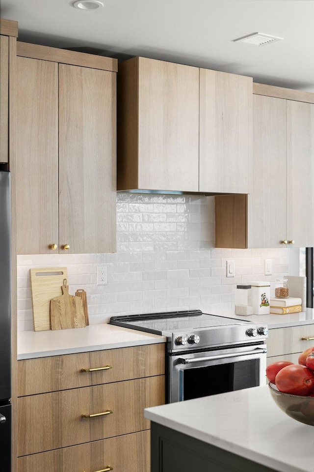 kitchen with decorative backsplash, light brown cabinetry, and stainless steel range with electric cooktop