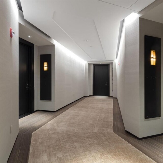 hall with light hardwood / wood-style flooring and elevator