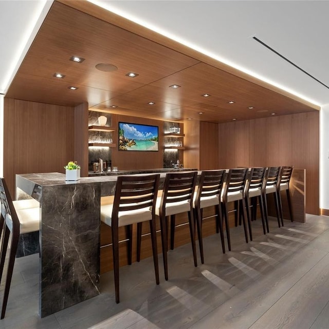 bar featuring indoor wet bar, wooden ceiling, recessed lighting, and wood walls