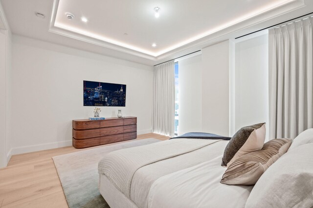 bedroom featuring a tray ceiling and light hardwood / wood-style floors