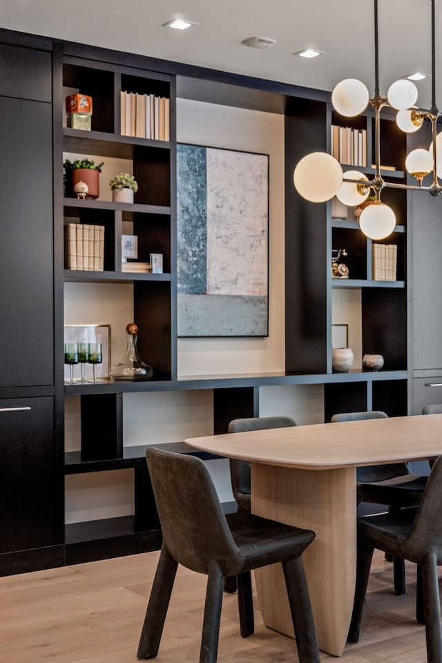 dining room featuring light hardwood / wood-style floors, a chandelier, built in shelves, and built in desk