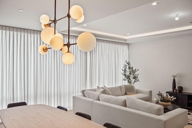 living area featuring recessed lighting, a tray ceiling, and a notable chandelier