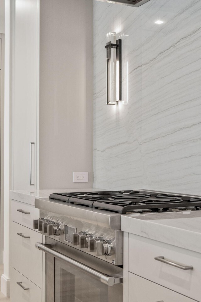 room details featuring white cabinetry, light stone countertops, and high end stainless steel range