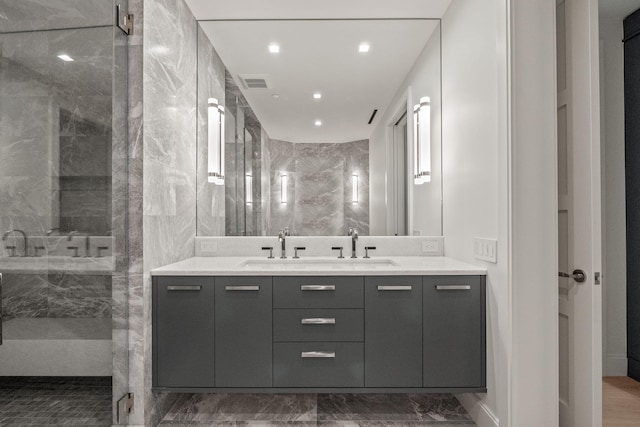 bathroom with tile patterned flooring, tile walls, tiled shower, and vanity