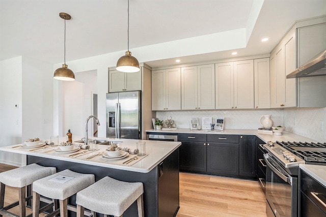 kitchen with sink, a kitchen island with sink, hanging light fixtures, and stainless steel appliances