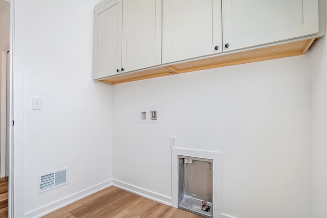 laundry area featuring cabinets, light hardwood / wood-style flooring, and washer hookup