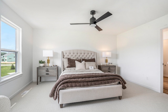 bedroom featuring ceiling fan, multiple windows, and light colored carpet