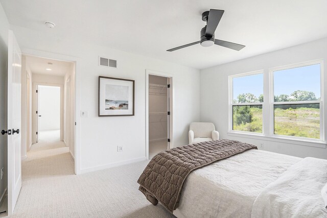 carpeted bedroom featuring a closet, a spacious closet, and ceiling fan