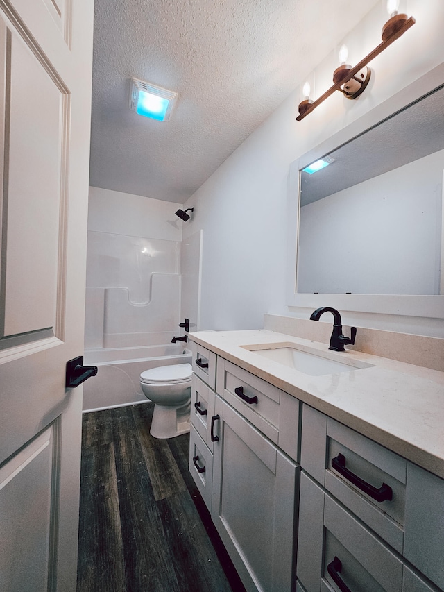 full bathroom featuring shower / washtub combination, a textured ceiling, toilet, wood-type flooring, and vanity