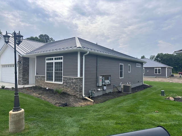 view of home's exterior with a lawn, central air condition unit, and a garage