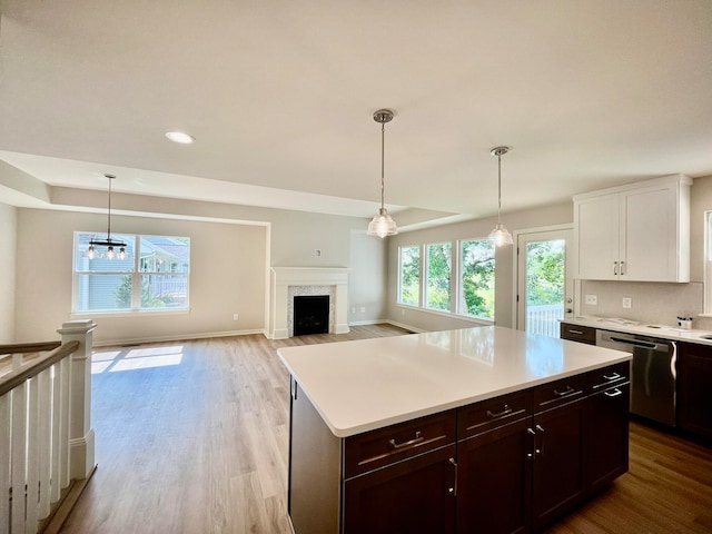 kitchen with light hardwood / wood-style flooring, dark brown cabinetry, decorative light fixtures, stainless steel dishwasher, and white cabinets