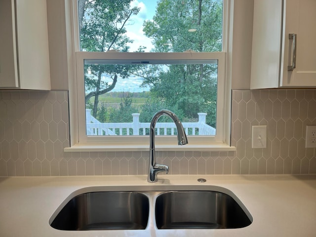 room details with white cabinetry, sink, and backsplash