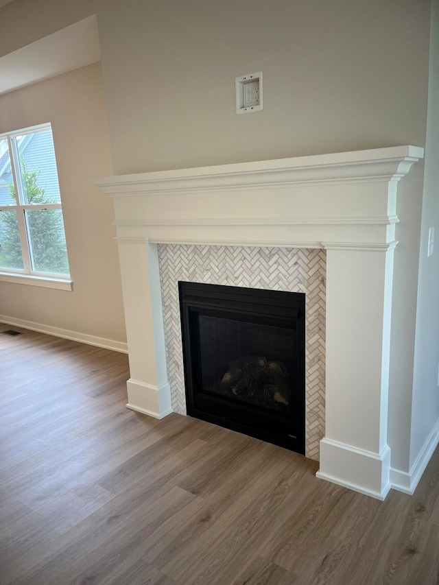 room details with a tiled fireplace and hardwood / wood-style flooring