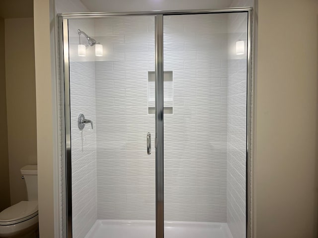 bathroom featuring toilet and a shower with shower door