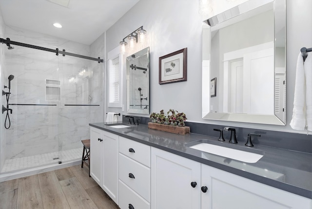 bathroom with hardwood / wood-style floors, an enclosed shower, and dual vanity