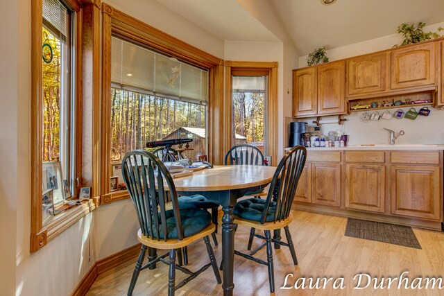 dining room with lofted ceiling, sink, plenty of natural light, and light wood-type flooring