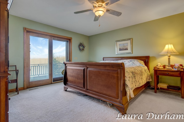 carpeted bedroom featuring access to exterior, ceiling fan, and a water view