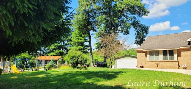 view of yard featuring a garage, an outdoor structure, and a playground