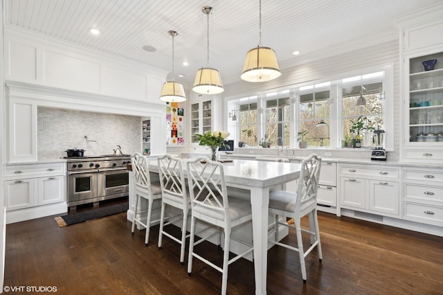 kitchen featuring white cabinets, a kitchen bar, dark hardwood / wood-style flooring, and double oven range