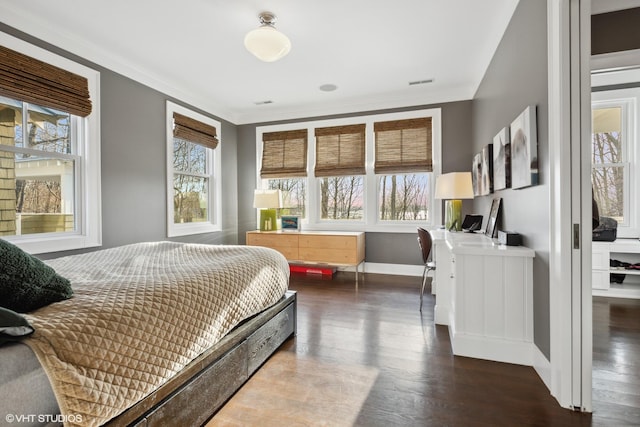 bedroom featuring hardwood / wood-style flooring, crown molding, and multiple windows