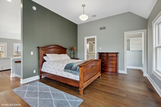 bedroom with a walk in closet, high vaulted ceiling, dark wood-type flooring, a closet, and connected bathroom