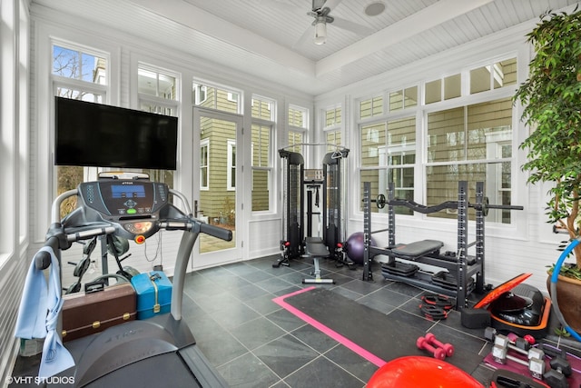 exercise room with ceiling fan, a raised ceiling, and tile patterned floors