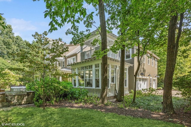 view of home's exterior with a balcony, a lawn, and a garage