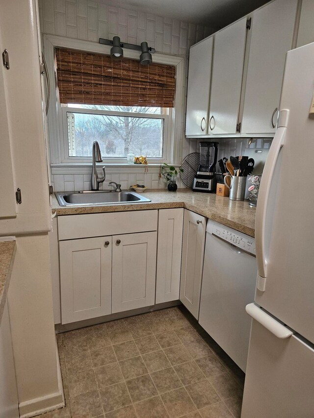 kitchen featuring tasteful backsplash, white appliances, light tile floors, sink, and white cabinetry