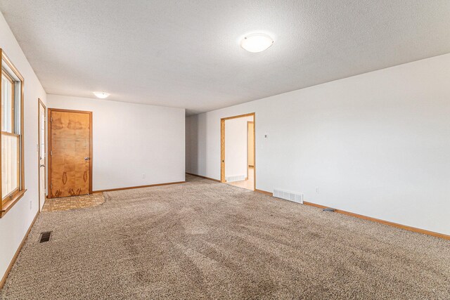 empty room with carpet and a textured ceiling