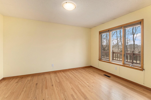 spare room featuring light wood-type flooring and a textured ceiling