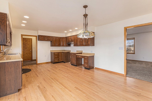 kitchen featuring light colored carpet, sink, and hanging light fixtures