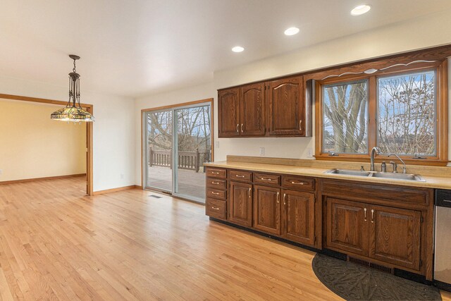 kitchen with decorative light fixtures, light wood-type flooring, sink, dishwasher, and dark brown cabinetry