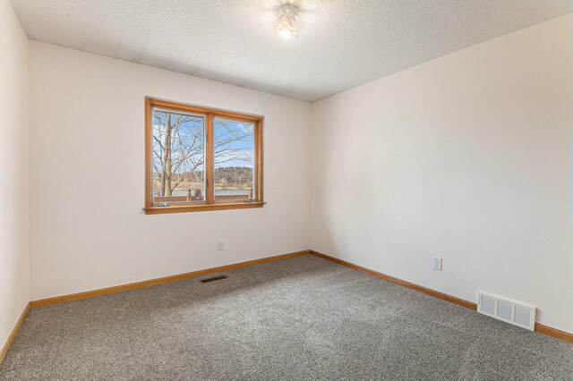 carpeted empty room with a textured ceiling