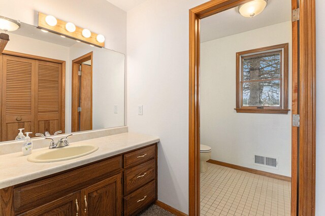 bathroom featuring toilet, tile flooring, and vanity