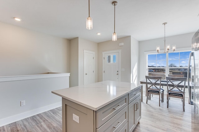 kitchen with decorative light fixtures, a chandelier, light hardwood / wood-style floors, gray cabinets, and a center island