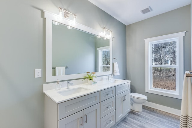 bathroom featuring toilet, a healthy amount of sunlight, double vanity, and hardwood / wood-style floors