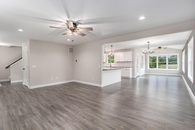 unfurnished living room featuring dark hardwood / wood-style flooring, sink, ceiling fan with notable chandelier, and lofted ceiling